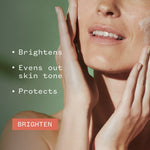 Woman with glowing skin gently cupping her face, showcasing brightening skincare benefits on sage green background
