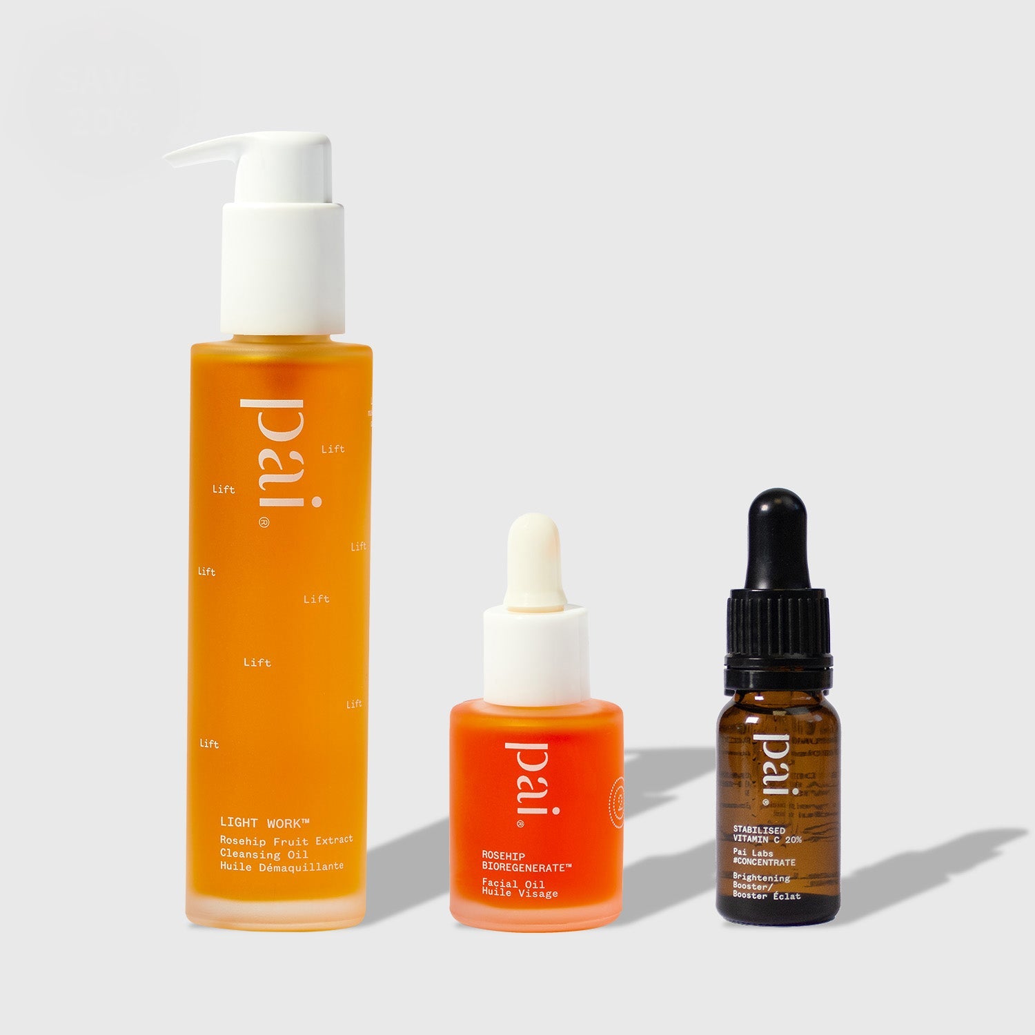 Three Pai Skincare products from the Brighten Starter Kit: orange Light Work cleansing oil, Rosehip BioRegenerate facial oil, and amber Vitamin C serum with dropper